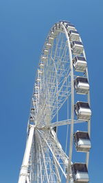 Low angle view of ferris wheel against clear blue sky