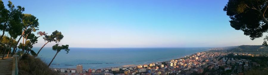 Panoramic view of townscape by sea against clear blue sky