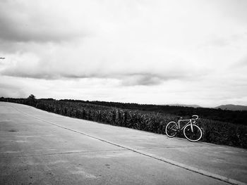 Bicycle parked on road against sky