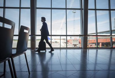 Side view of businessman walking with luggage at airport