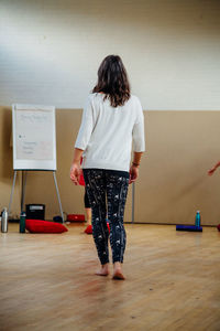 Rear view of woman standing against wall at home