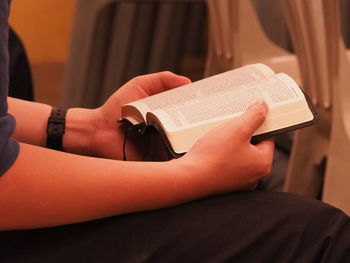 Midsection of man reading bible