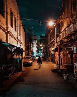 People on street amidst illuminated buildings in city at night