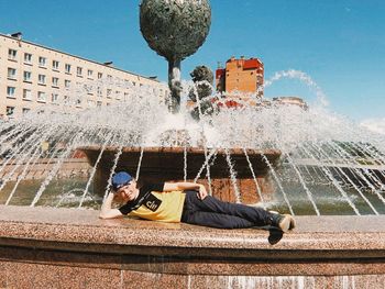 Rear view of woman sitting on fountain