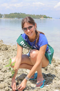 Portrait of smiling young woman sitting on land