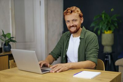 Portrait of young man using laptop at office