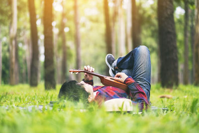 Young man playing guitar in forest