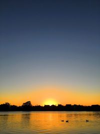 Scenic view of lake against clear sky during sunset