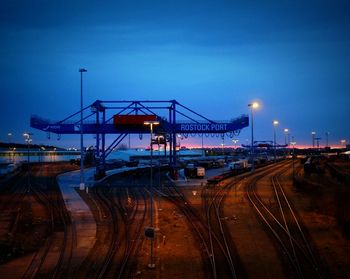 Railroad tracks at commercial dock against sky at twilight