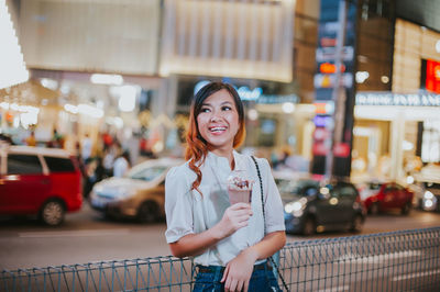 Portrait of smiling young woman standing in city