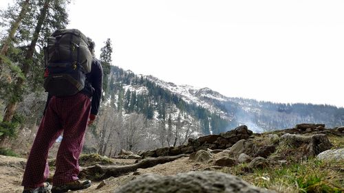 Rear view of man standing on mountain against sky