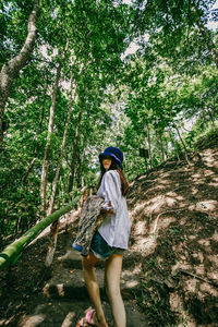 Full length of woman standing by tree in forest