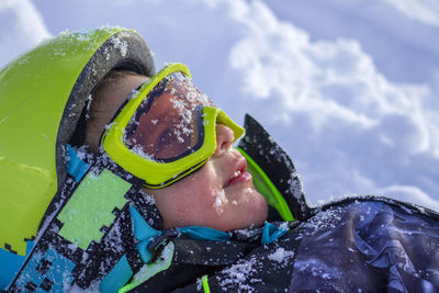 Portrait of boy in helmet and goggles lying in snow