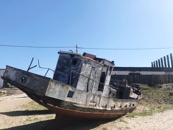 Abandoned boat on sand against clear sky