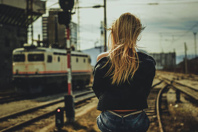 Rear view of woman standing by train against sky