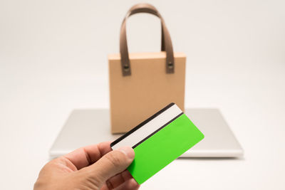 Cropped hand of woman using mobile phone against white background