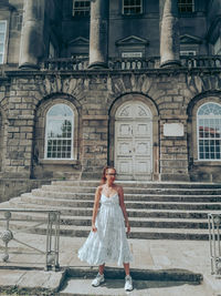 Full length of woman sitting on staircase of building