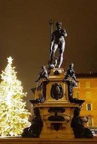 Low angle view of statue against illuminated building against clear sky