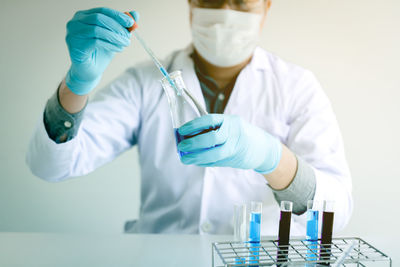 Midsection of scientist examining chemical in laboratory