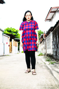 Full length portrait of woman standing against building