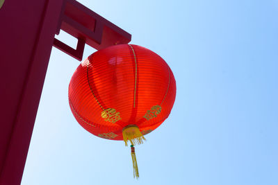 Low angle view of lantern hanging against clear blue sky