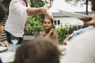 Midsection of senior woman taking plate from daughter-in-law at outdoor dining table