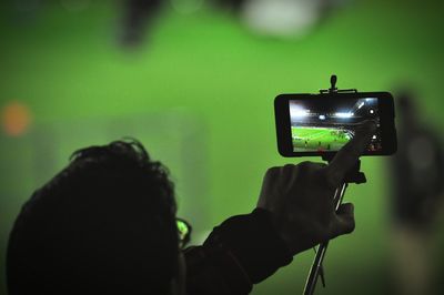 Cropped image of man holding selfie stick at football stadium