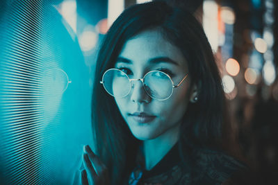 Close-up portrait of young woman standing outdoors at night