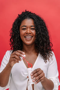 Portrait of smiling young woman drinking milk against yellow background