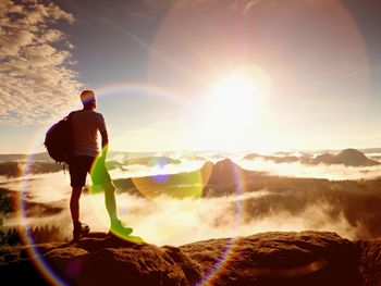 Flare. thinking hiker in black on rocky peak. ginger hair man in black pants on cliff. wonderful day