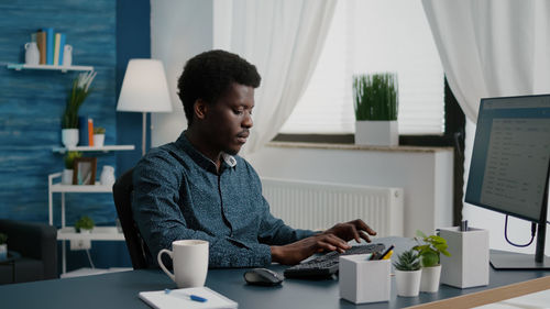 Man using mobile phone while sitting on table