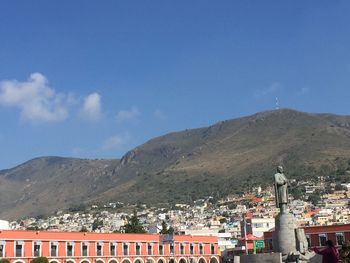 Cityscape in front of mountains against blue sky