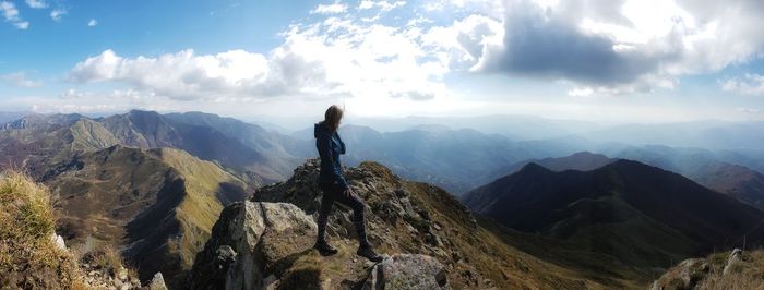 Side view of woman standing on rock against sky