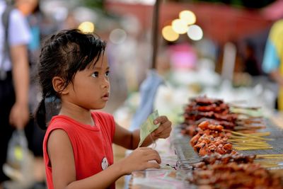 Girl buying barbecue at market stall