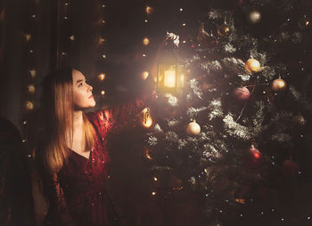 Woman looking at illuminated christmas tree at night