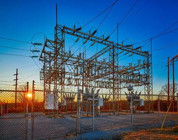 Low angle view of electricity pylon against clear blue sky