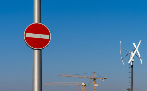 Low angle view of road sign against clear blue sky