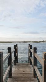 Wooden pier over sea against sky