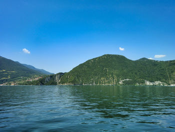 Scenic view of sea and mountains against blue sky