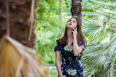 Young woman standing by tree