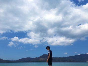 Man standing by lake against sky