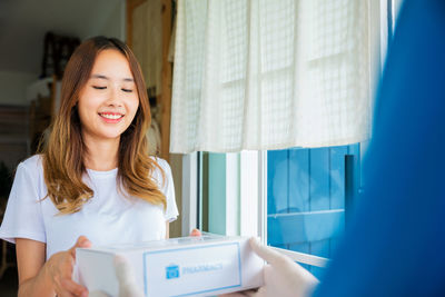 Portrait of young woman using digital tablet while standing at home