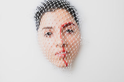 Close-up portrait of young woman with face covered by net taking milk bath