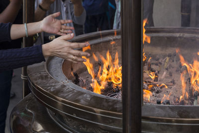 Cropped hands of woman over fire pit