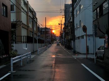 Street amidst buildings against sky during sunset