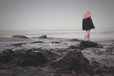 Girl walking by submerged tree stumps at beach