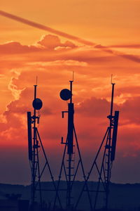 Silhouette communications towers against orange sky
