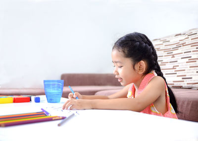 Girl coloring on paper at home
