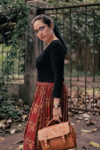 Portrait of young woman standing against tree