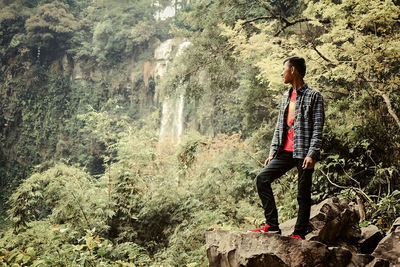 Young woman standing on rock against trees